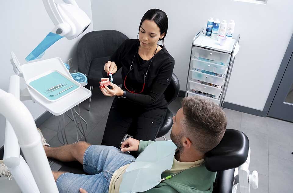 Patient cleaning dental bridge using floss and oral hygiene tools after treatment in North Miami Beach dental clinic