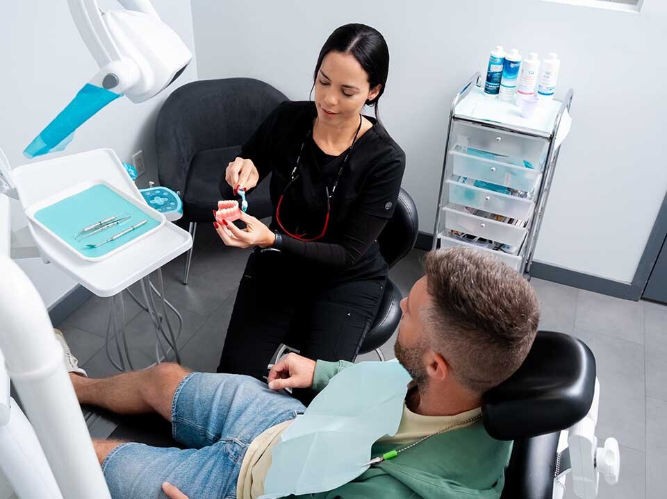 Dentist explaining dental bridge treatment using teeth model at Dental Pearl Miami in North Miami Beach FL