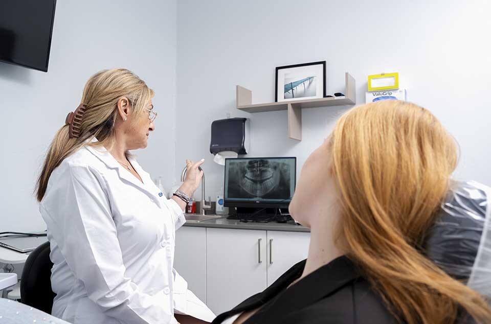 Dentist performing oral exam and discussing treatment plan with patient at Dental Pearl in North Miami Beach
