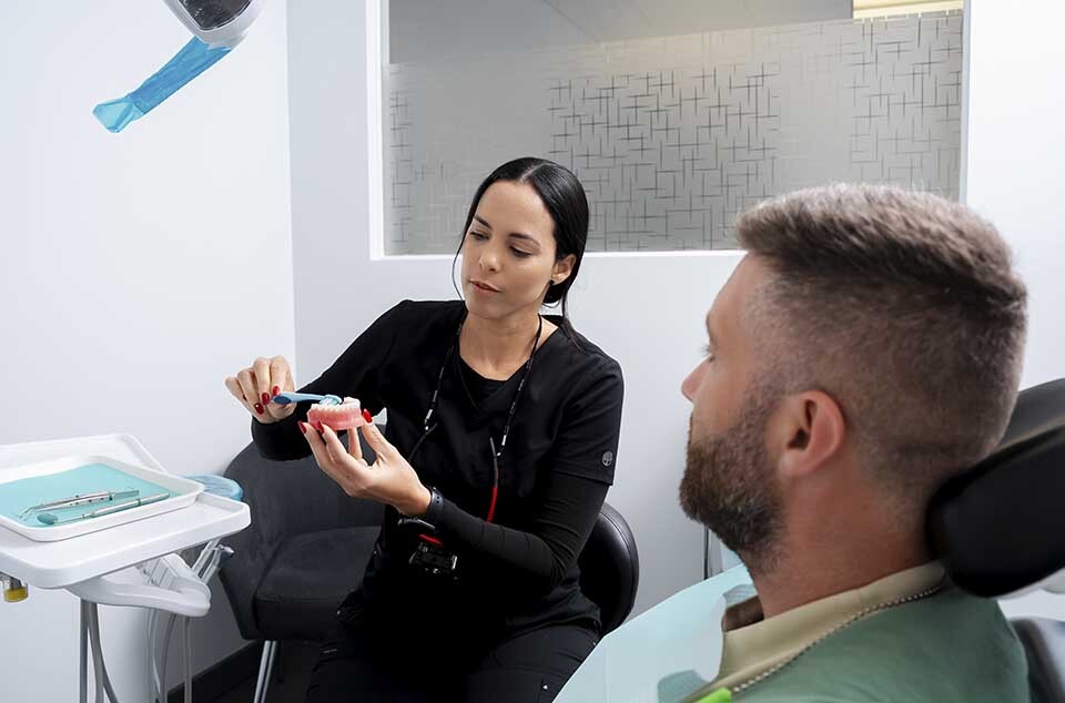 Dentist examining denture and discussing repair process with patient at Dental Pearl Miami in North Miami Beach FL