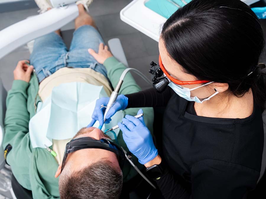 Dentist performing dental treatment and cleaning on patient at Dental Pearl Miami in North Miami Beach FL