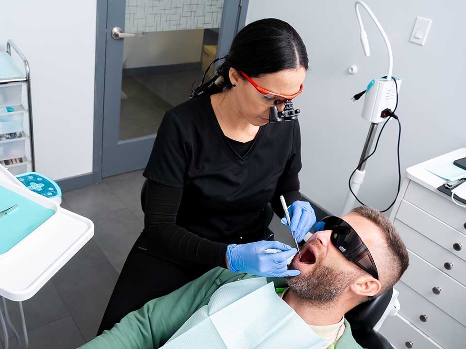 Dentist performing professional teeth cleaning for gingivitis treatment at Dental Pearl in North Miami Beach FL to remove plaque and improve gum health