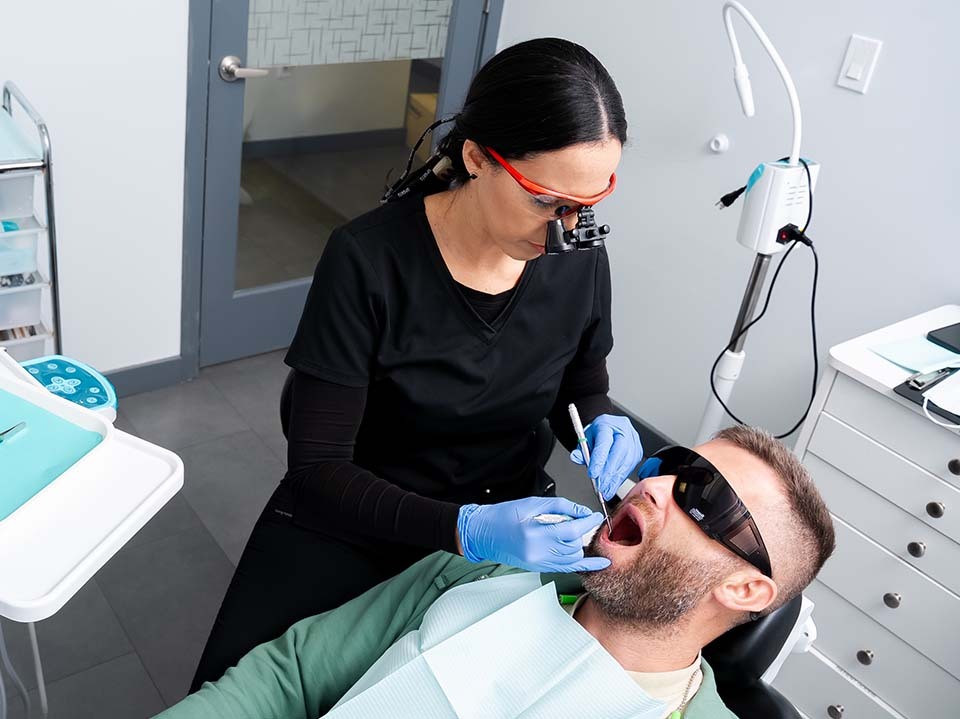 Dentist performing scaling and root planing for periodontitis treatment in North Miami Beach FL at Dental Pearl Miami