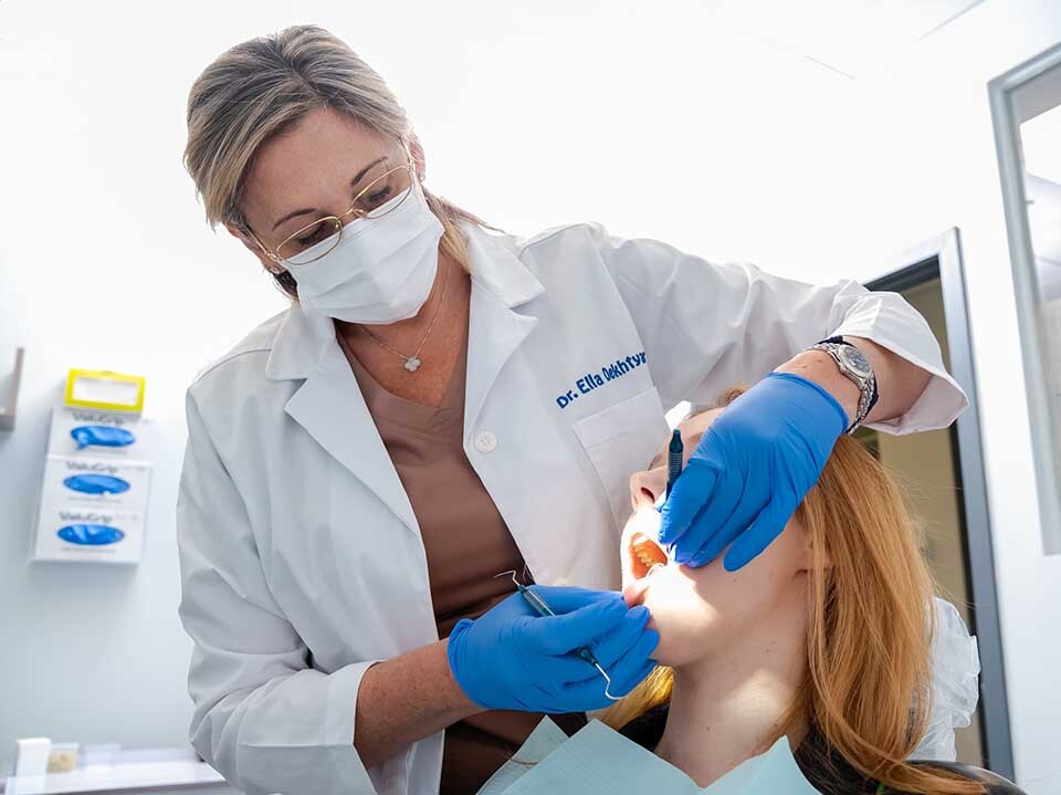 Dentist performing professional teeth cleaning on patient at Dental Pearl in North Miami Beach FL removing plaque and tartar for improved oral health