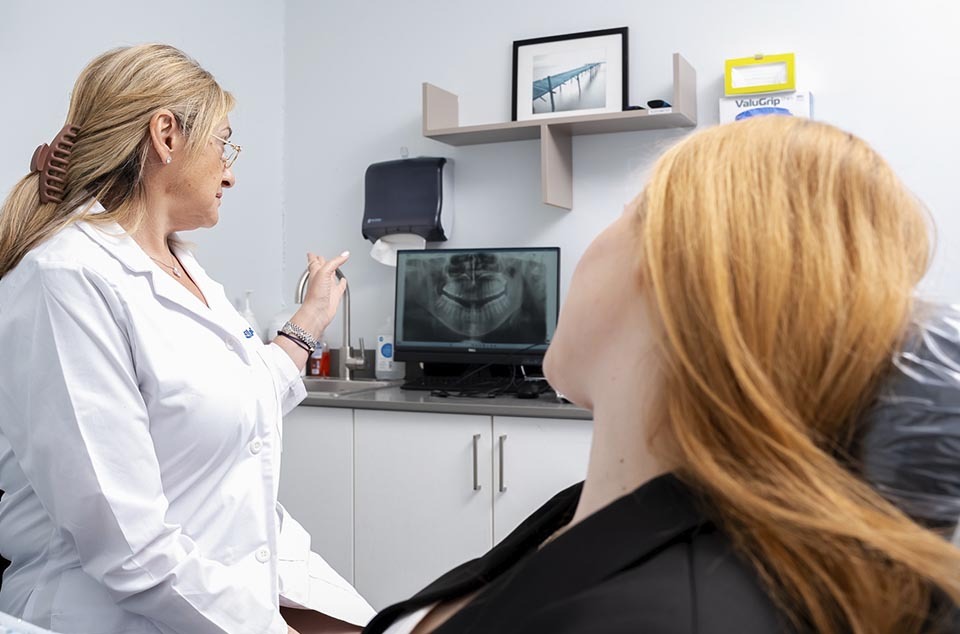 dentist reviewing dental x-ray to plan All-on-4 implant placement and jawbone support in North Miami Beach FL