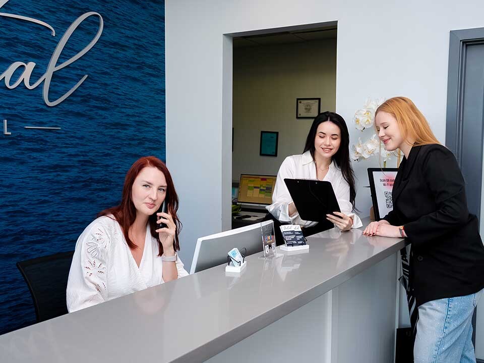 Patient checking in at Dental Pearl Miami front desk in North Miami Beach FL with friendly staff assistance