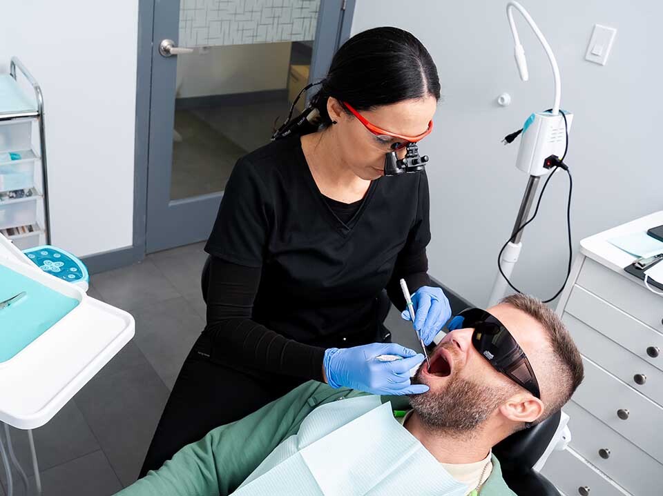 Dentist performing emergency root canal treatment to relieve tooth infection at Dental Pearl Miami in North Miami Beach FL