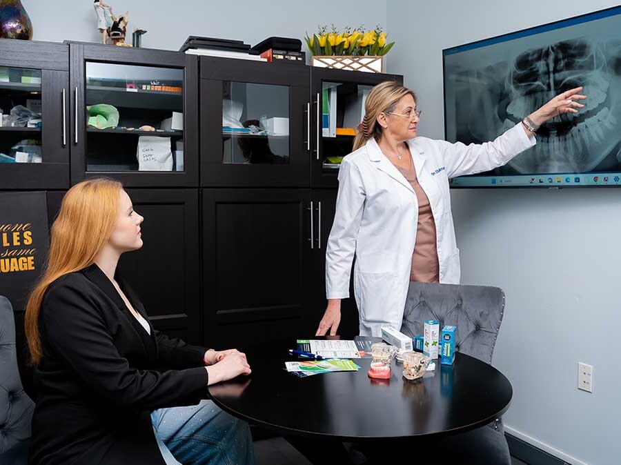 dentist explaining orthodontic results and retainers using dental X-ray during consultation at Dental Pearl Miami in North Miami Beach FL